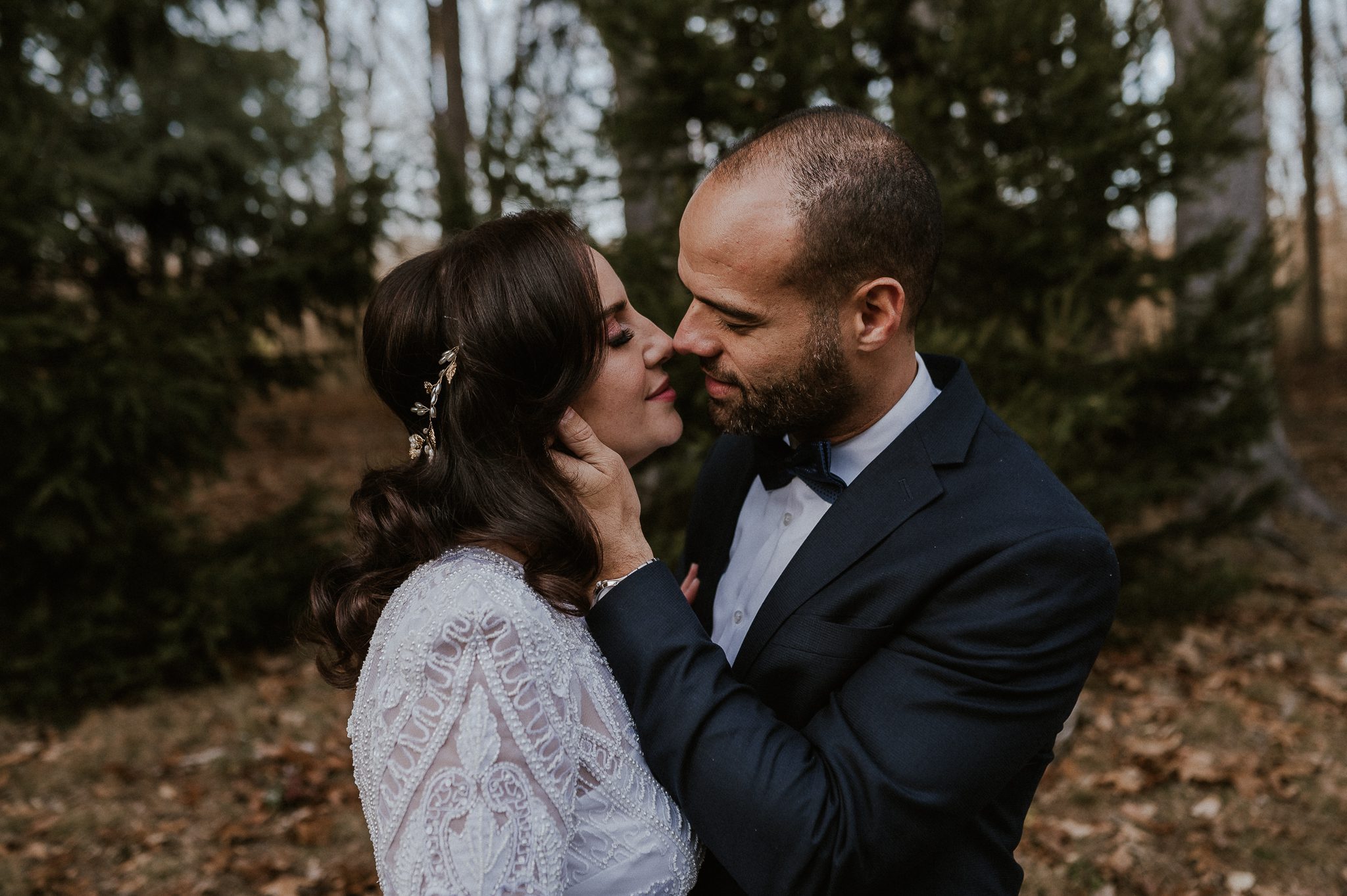 bride and groom stand embrace for a kiss in the woods