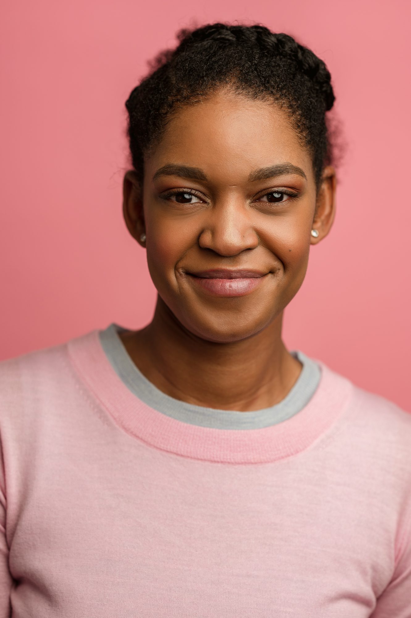 woman poses in pink shirt with pink background for headshot