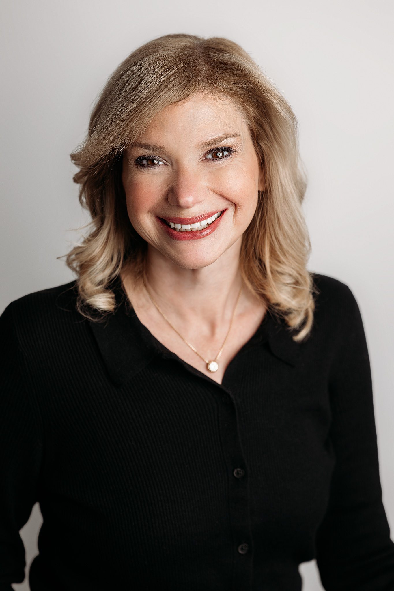 Blonde woman poses for her professional headshot at Joan Marie Photography's studio in Scotch Plains NJ