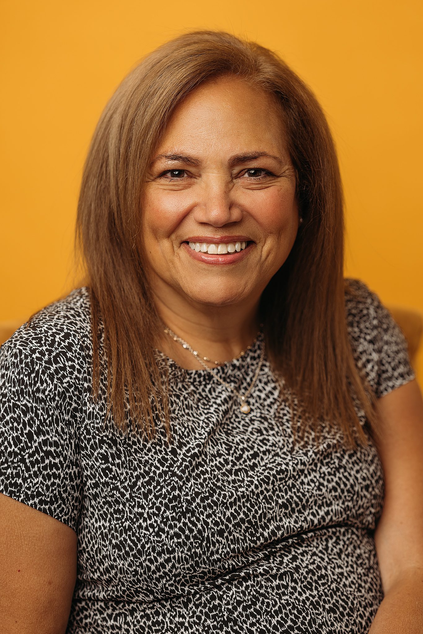 Professional woman headshot infront of colorful marigold backdrop