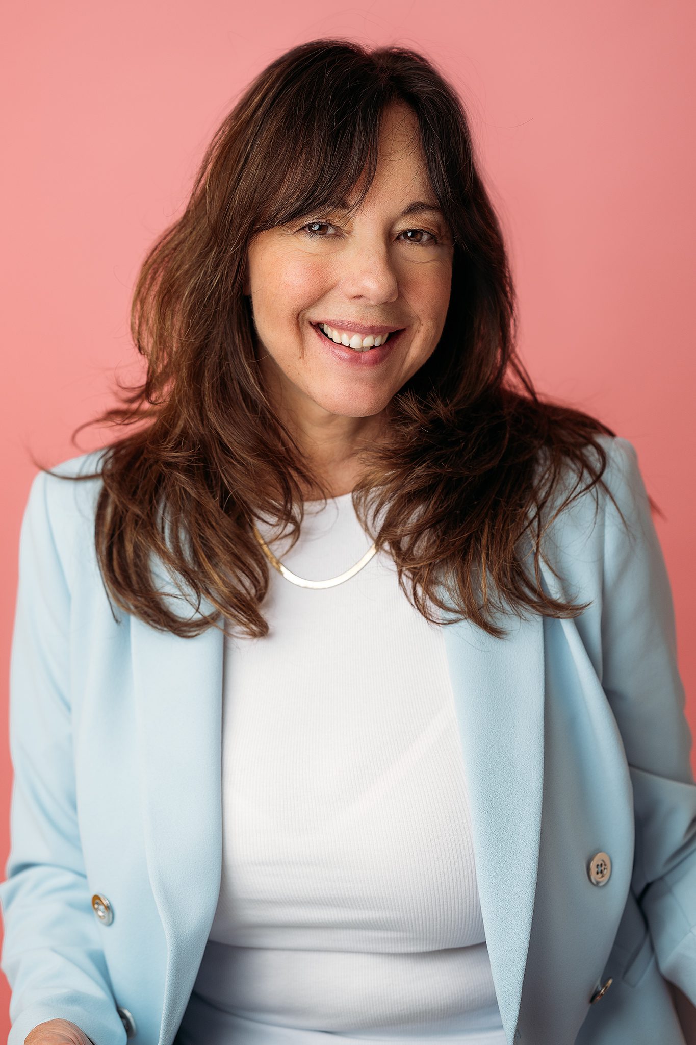 therapist poses for headshot on a colorful pink backdrop