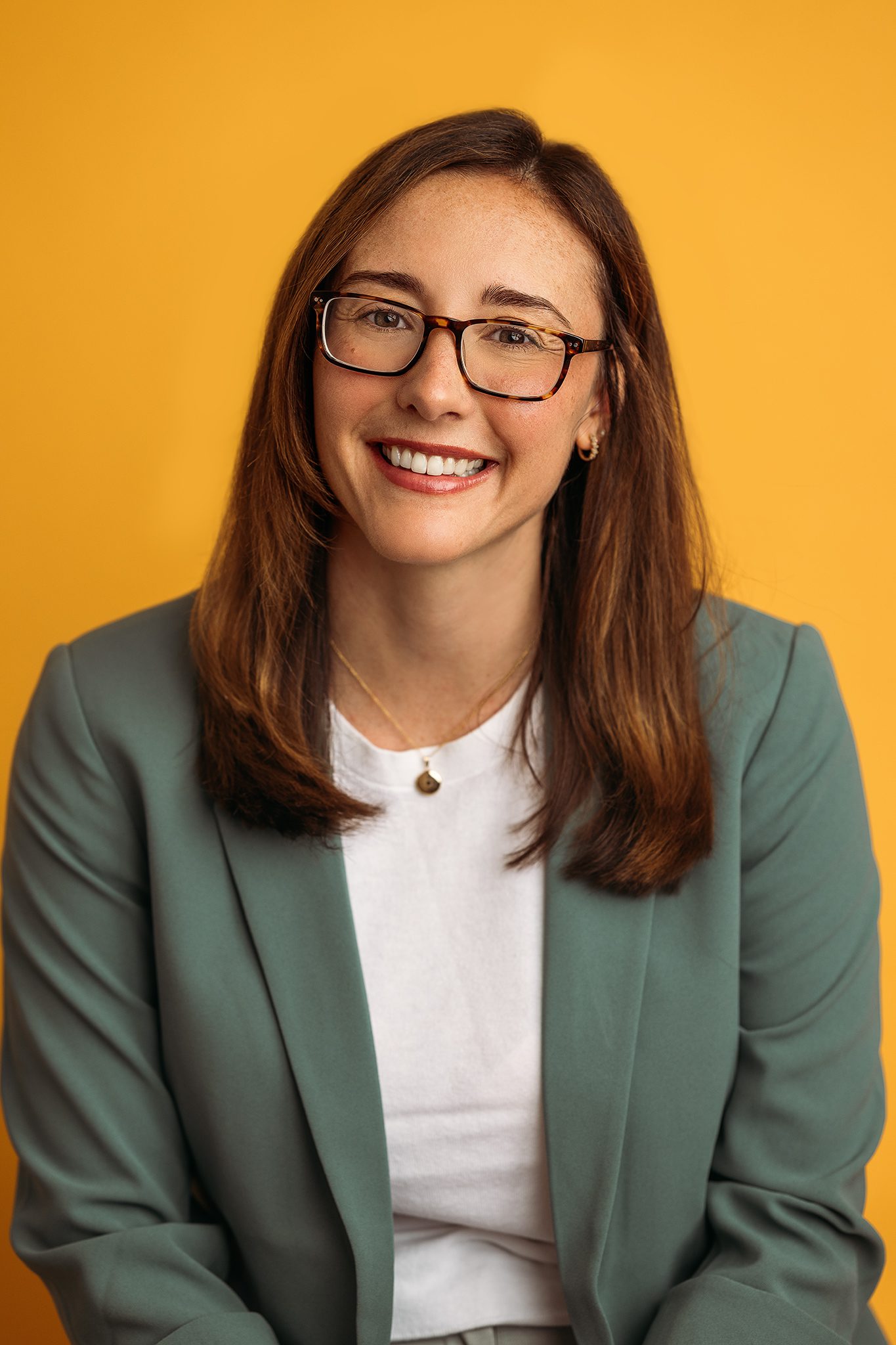 therapist poses for headshot on a colorful marigold backdrop