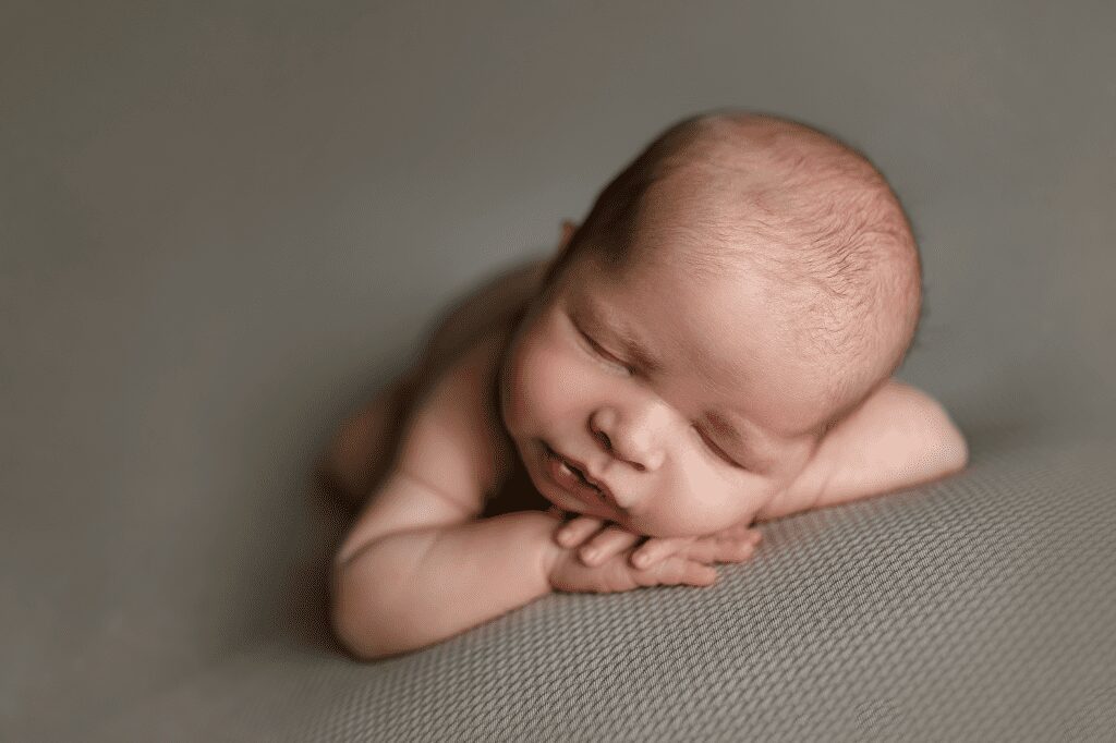 newborn baby rests head on hands at his newborn photoshoot in scotch plains with Joan Marie Photography