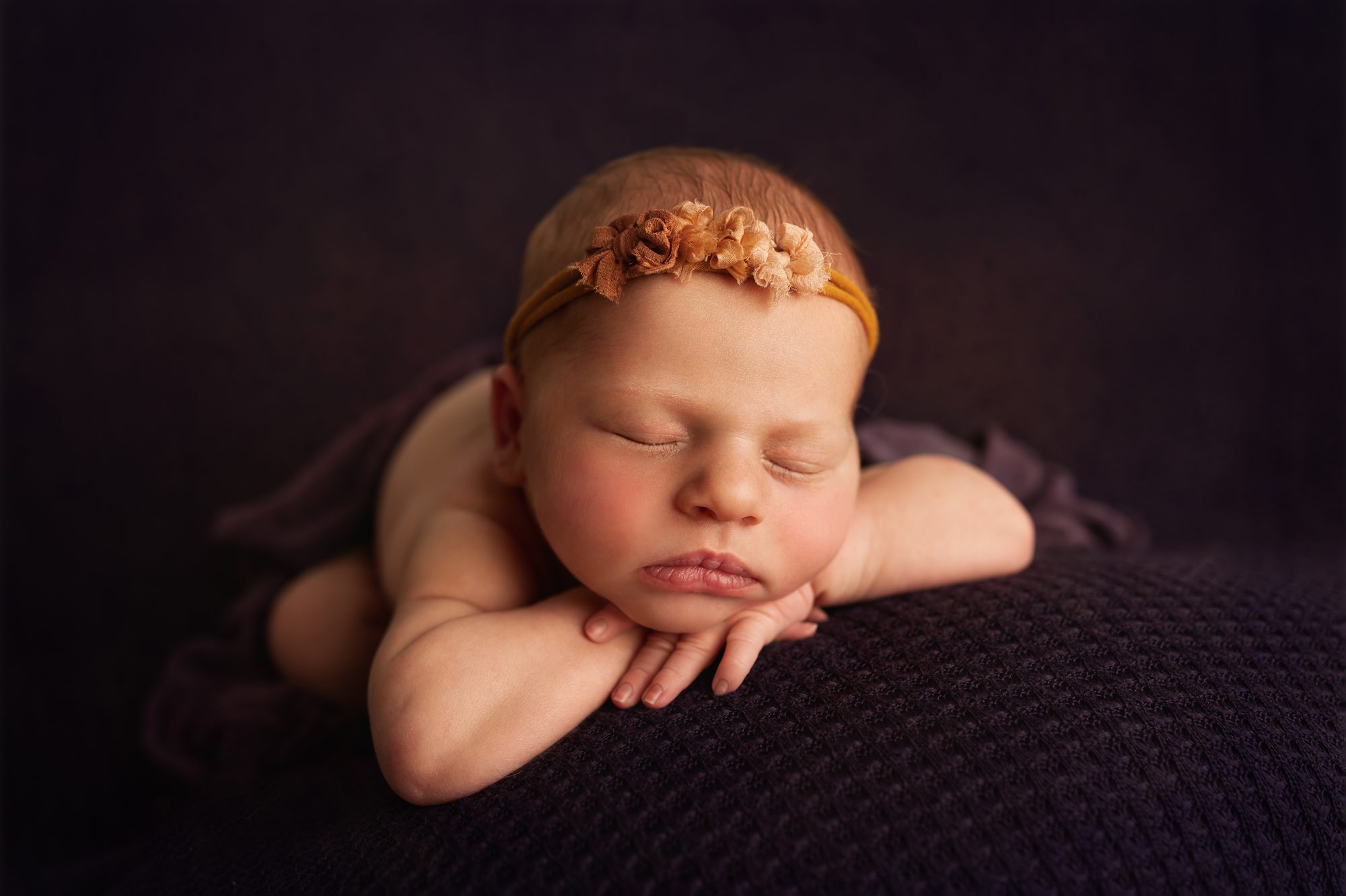 newborbn baby girl on purple backdrop at her scotch plains newborn photography session
