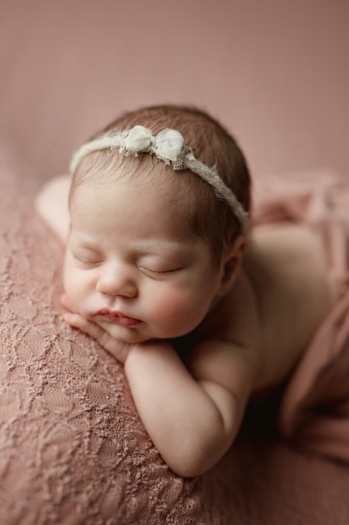 newborn girl on a pink backdrop at photoshoot with joan marie photography in scotch plains nj