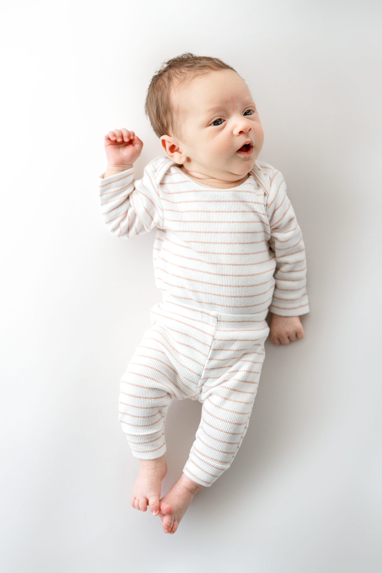 newborn boy in striped outfit on white background