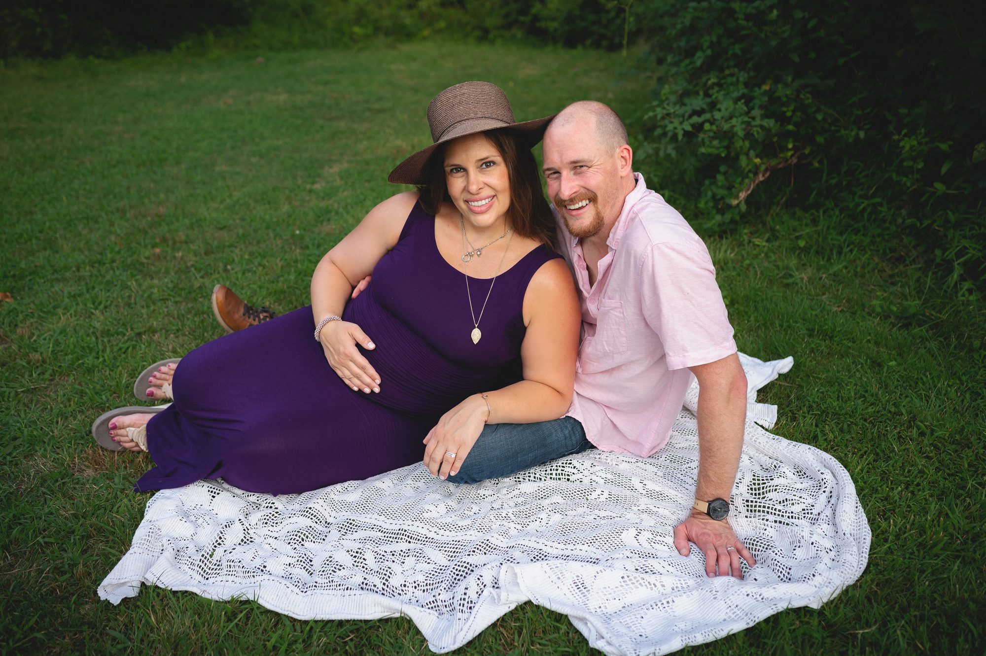 pregnant mom and hubby sit on blanket