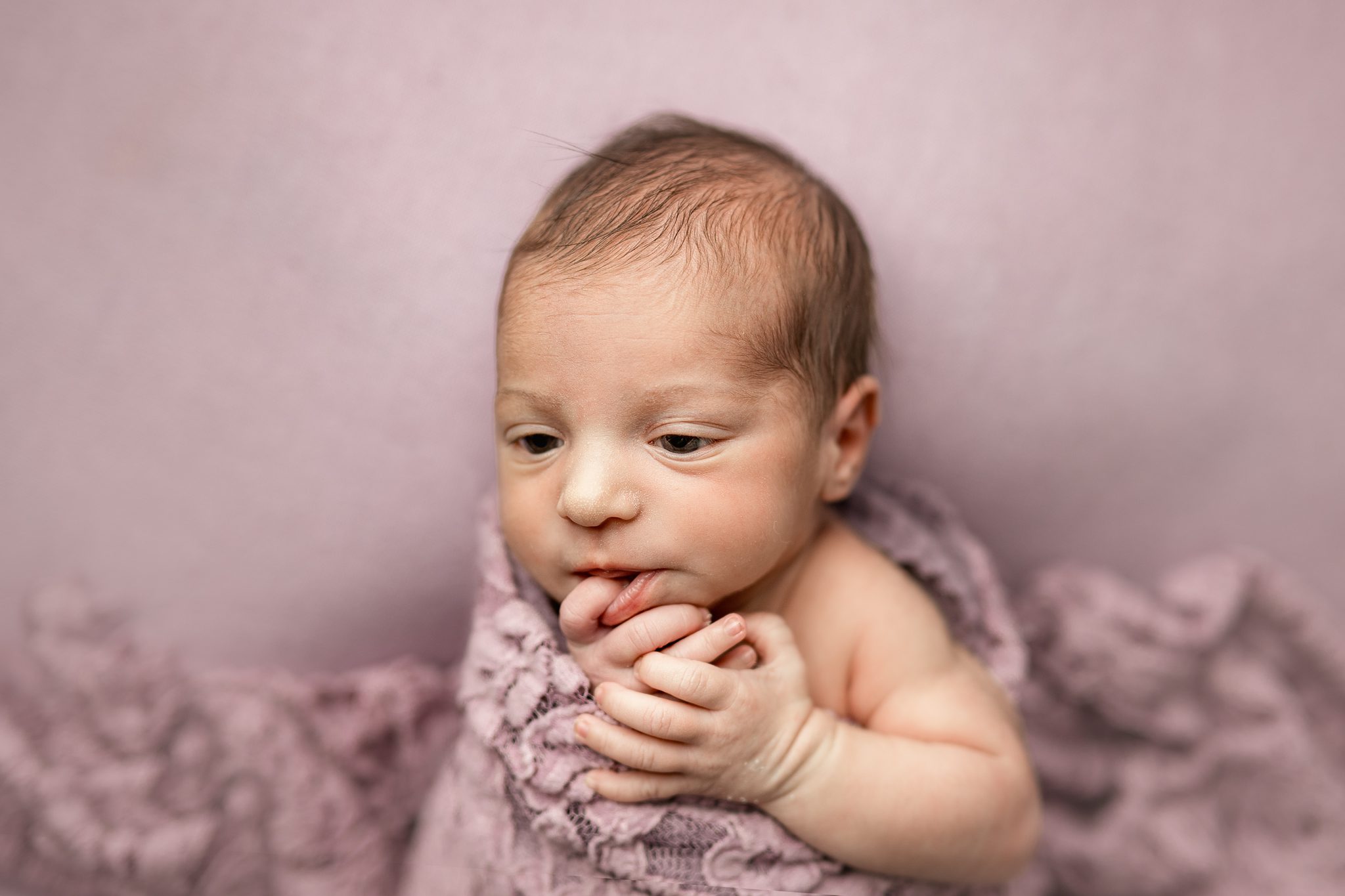 newborn baby sleepily opens eyes