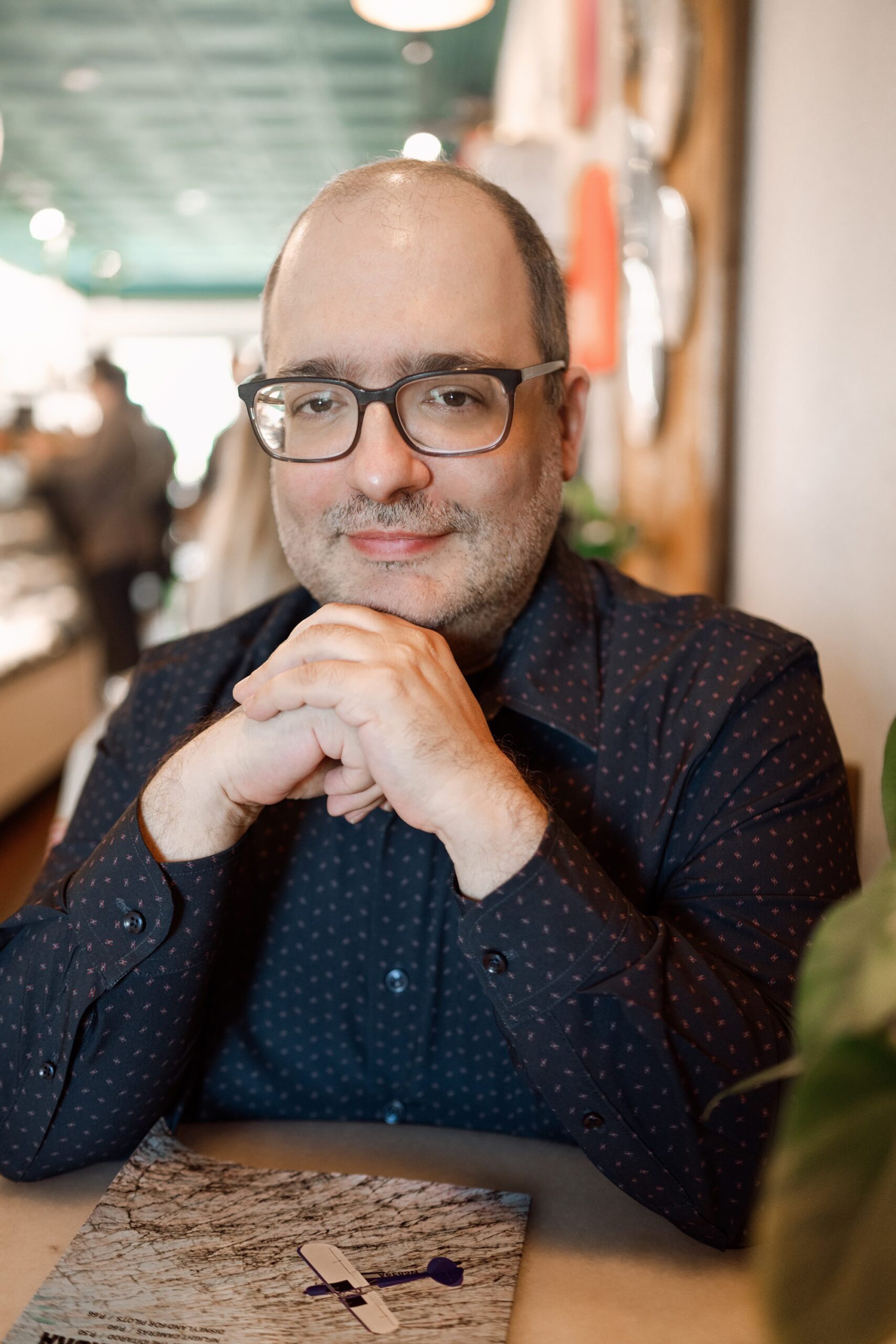 man in nice button down shirt sits in a relaxed pose at LOKL Coffee for his dating profile session in Morristown NJ with Joan Marie Photography