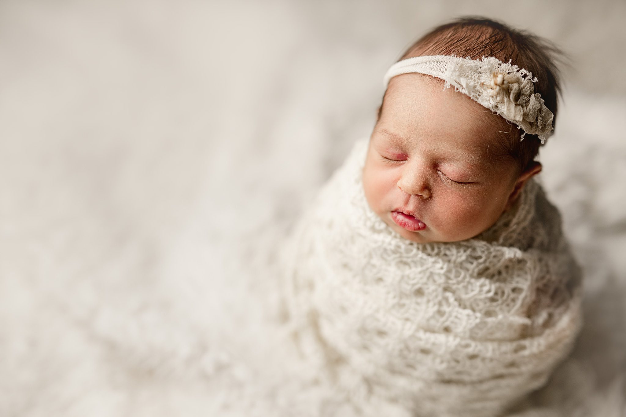 newborn baby girl poses on a white backdrop at her Newborn Photoshoot with Joan Marie Photography