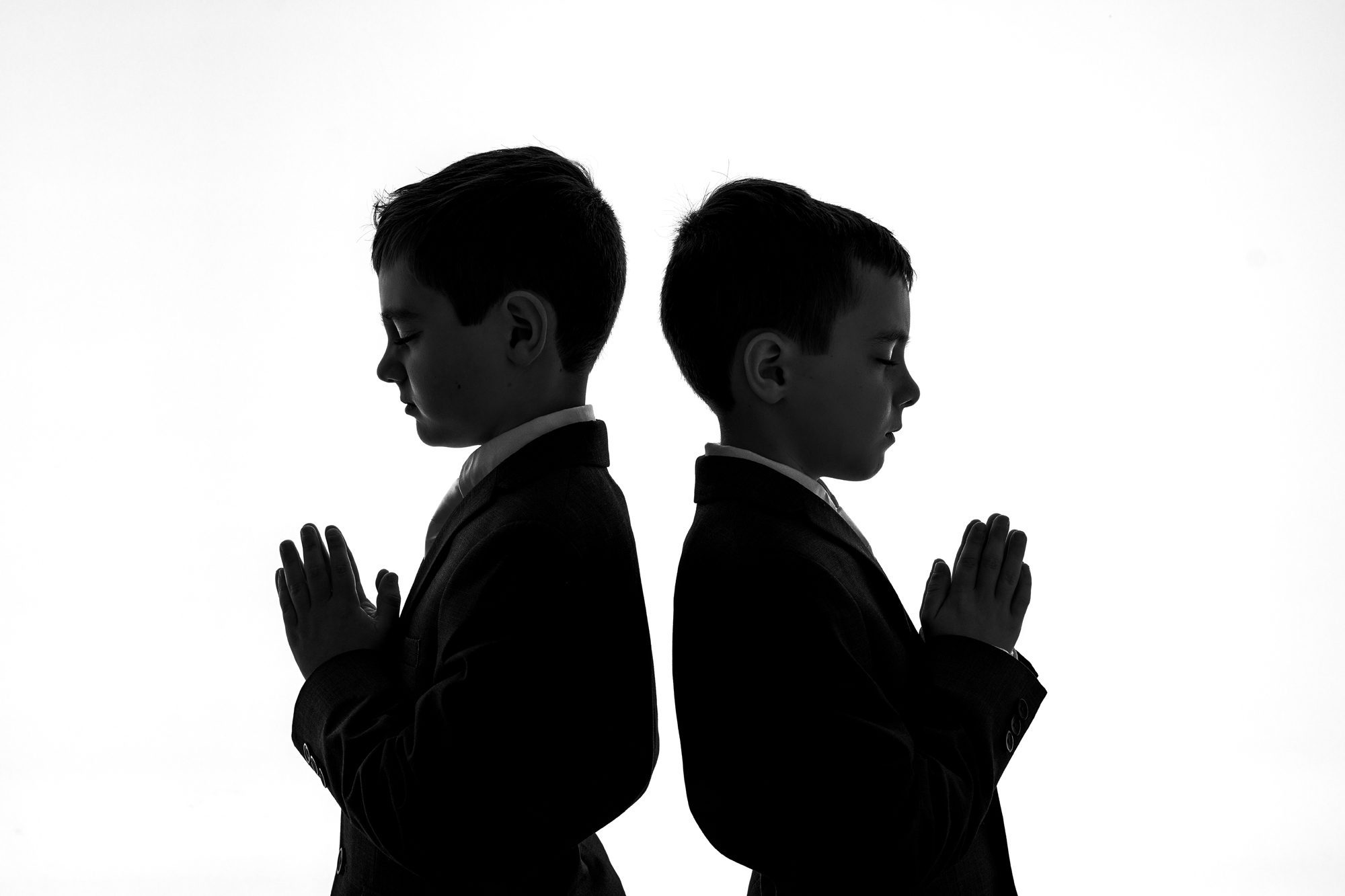 silhouette of twin boys with their hands in prayer at their communion photoshoot in Scotch Plains NJ with Joan Marie Photography