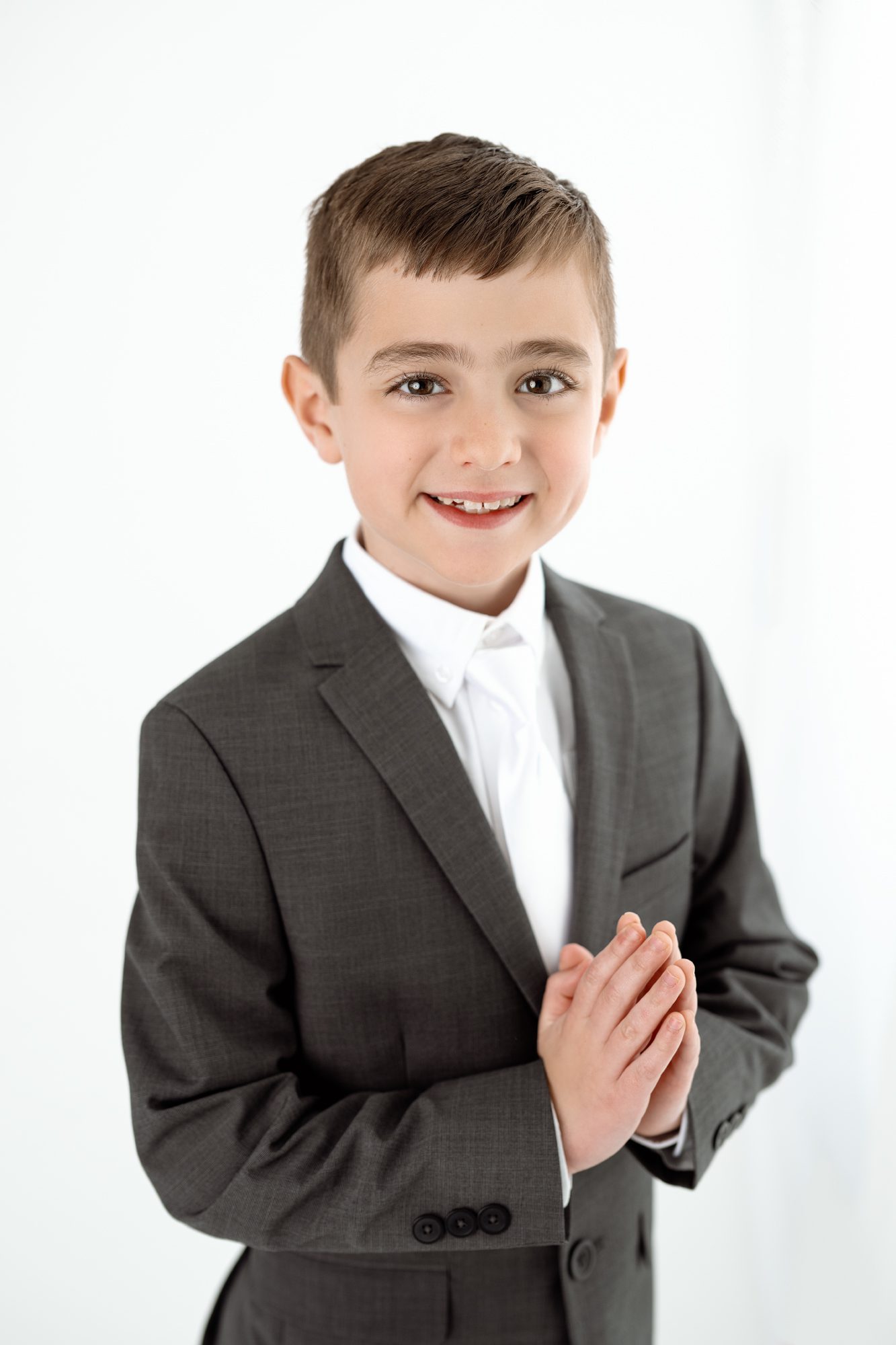 young boy poses with his hands in prayer for his communion photoshoot in scotch plains with joan marie photography
