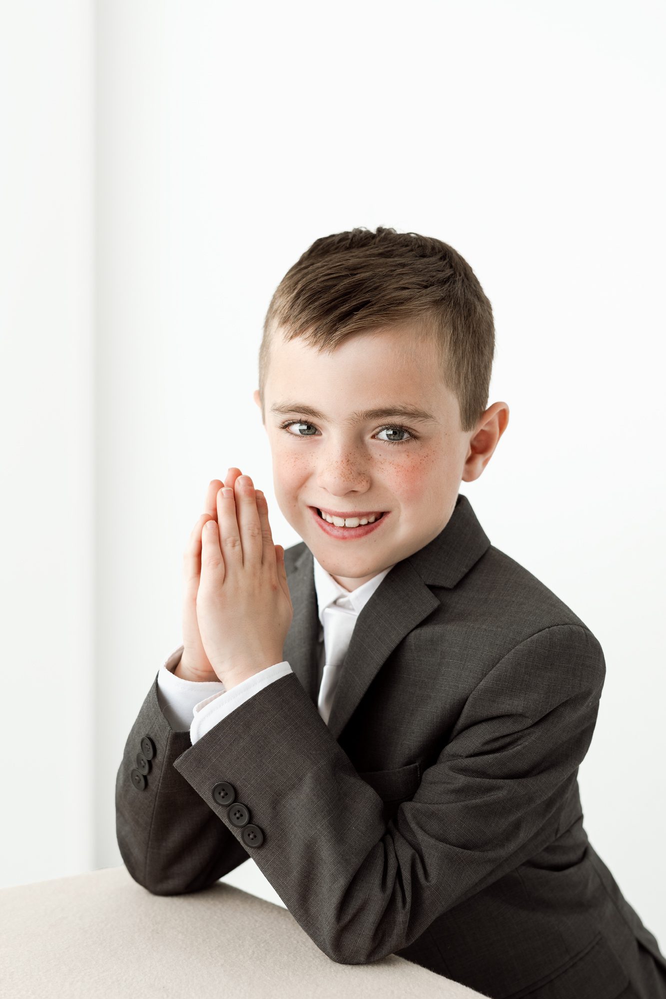 young boy poses with his hands in prayer for his communion photoshoot in scotch plains with joan marie photography