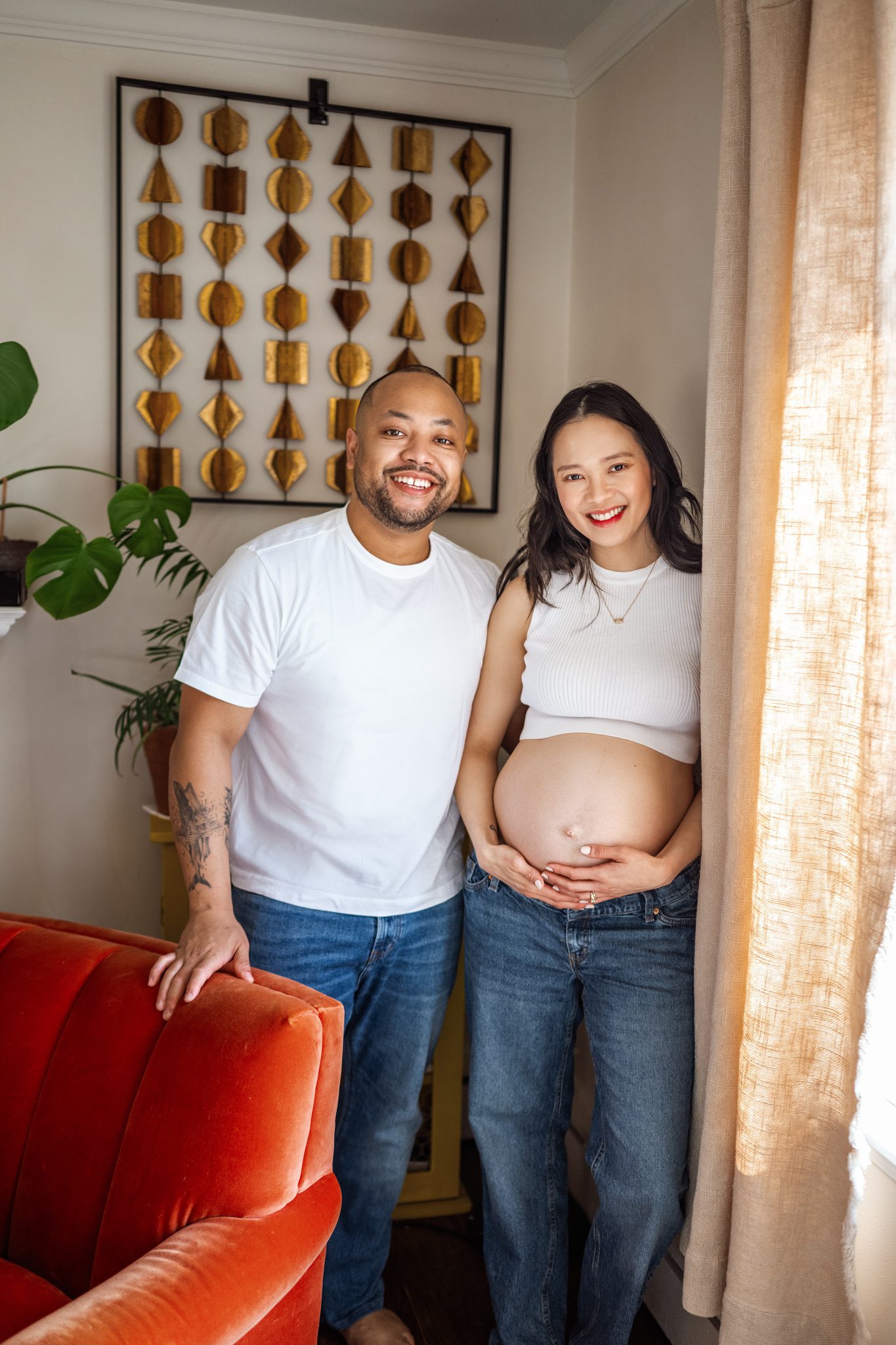 husband and wife smile in their living room in-home maternity session in scotch plains nj with joan marie photography