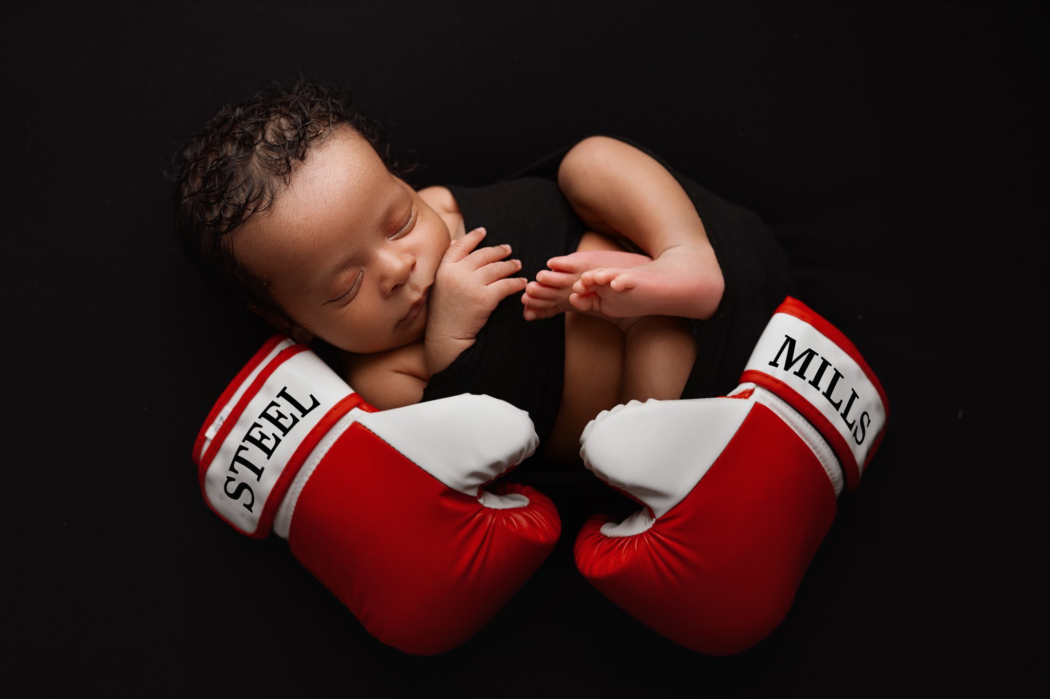newborn baby held in boxing gloves representing his late grandfather, Arthur 