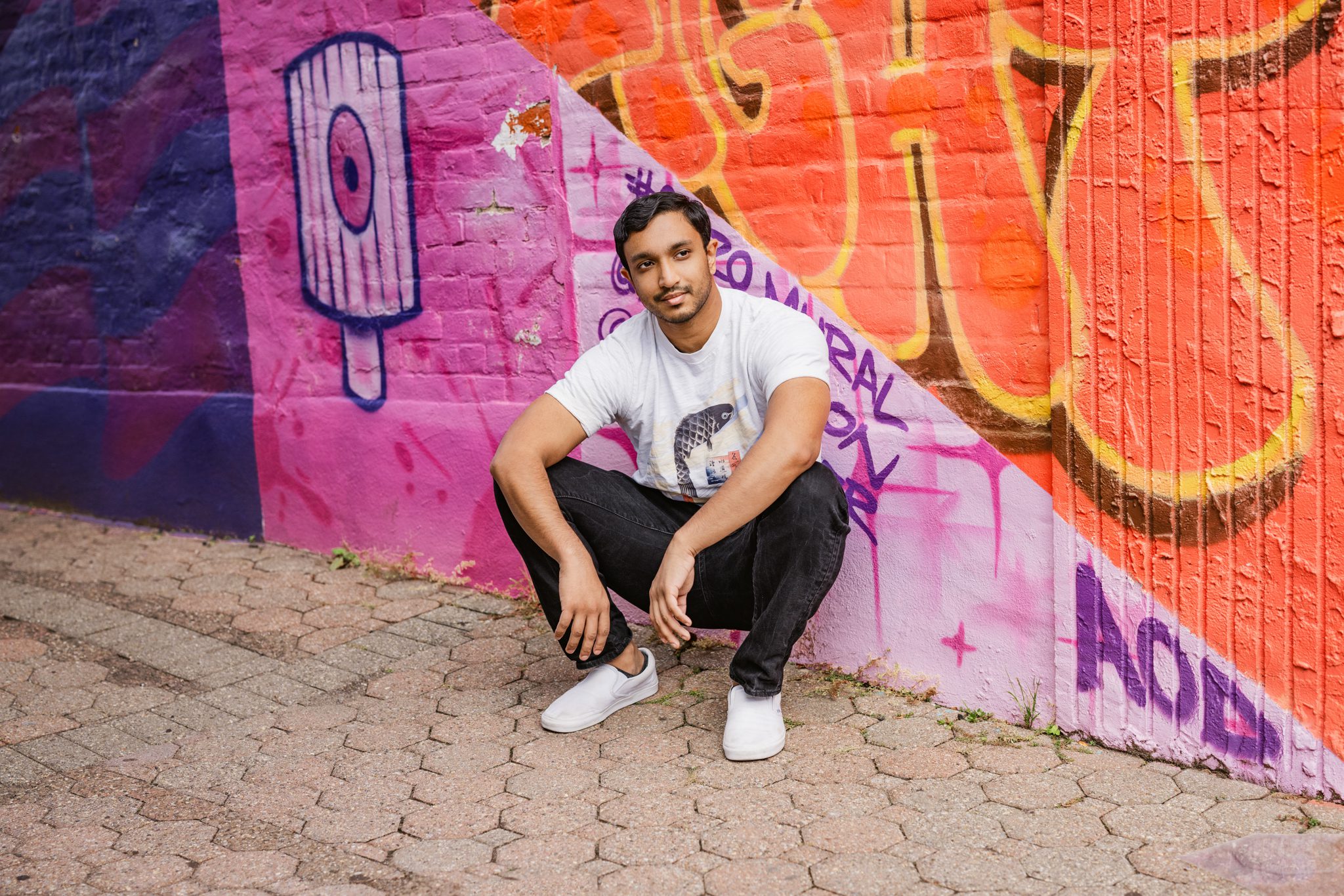 young man posing in front of graffiti wall for a dating photo session