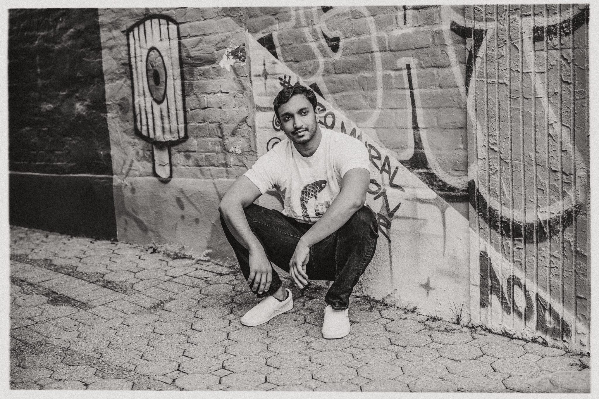 black and white photo of young man posing in front of graffiti wall for a dating photo session