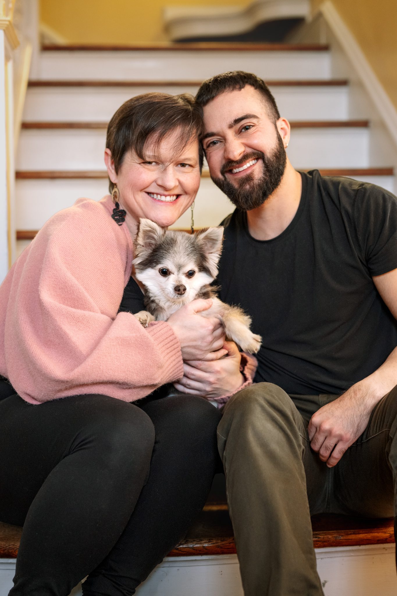 mom dad and little dog smiling on stairs