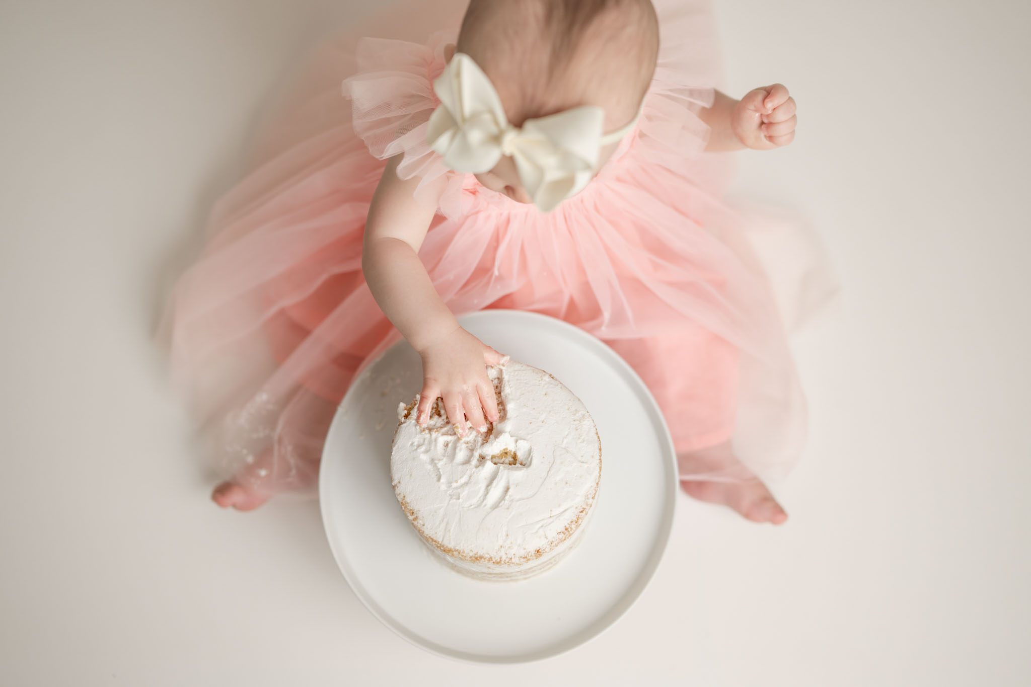 overhead shot of little girl with her hand in cake at cake smash session