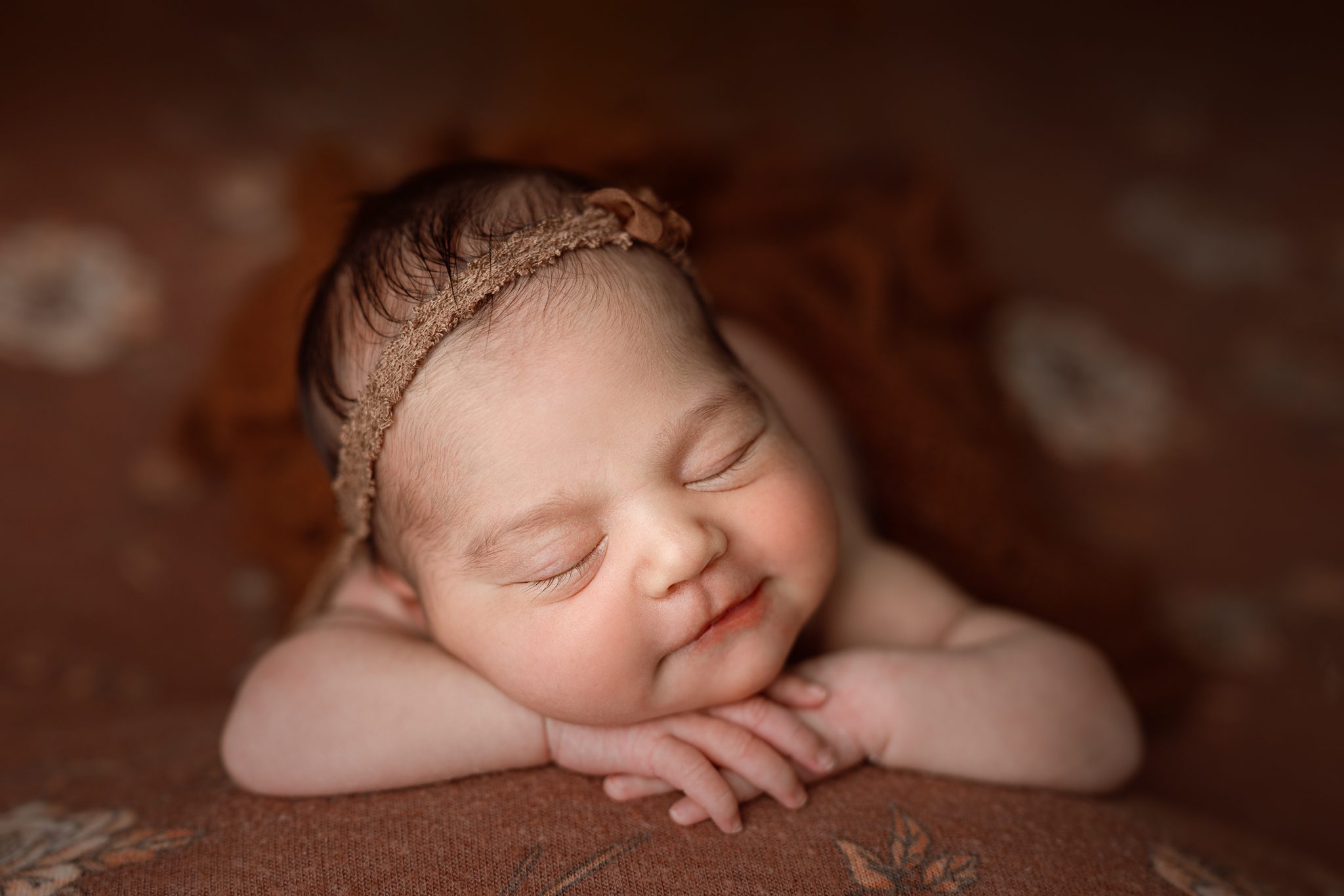 Artistically posed baby girl on a floral fabric backdrop during a custom newborn session in Scotch Plains