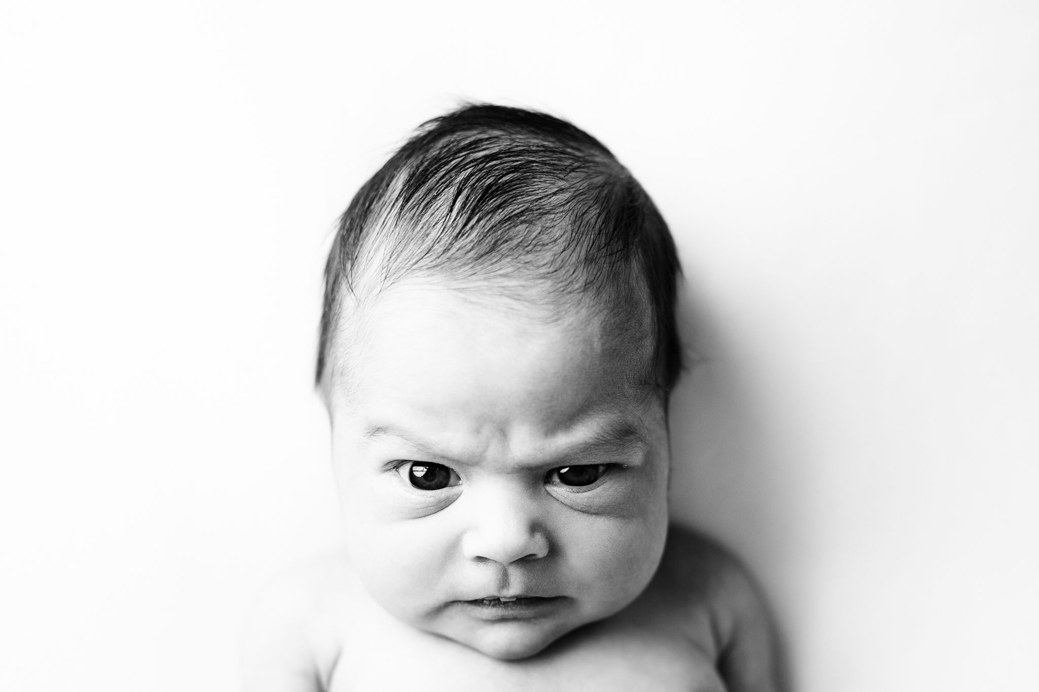 Close-up black and white newborn personality portrait capturing a sweet facial expression of a baby girl