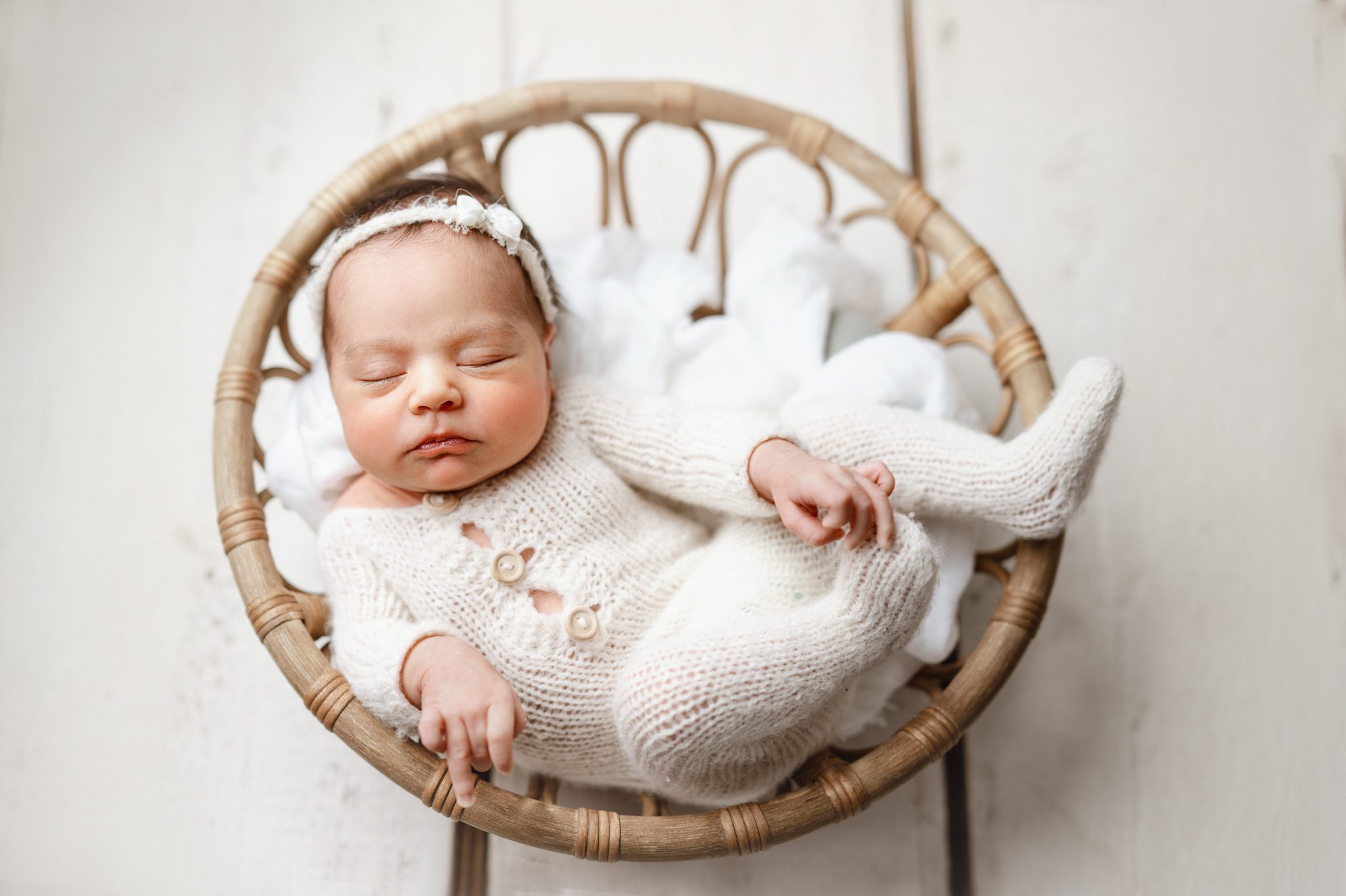 A meticulously posed newborn baby girl sleeping in a custom-curated wooden bowl in a Scotch Plains photography studio