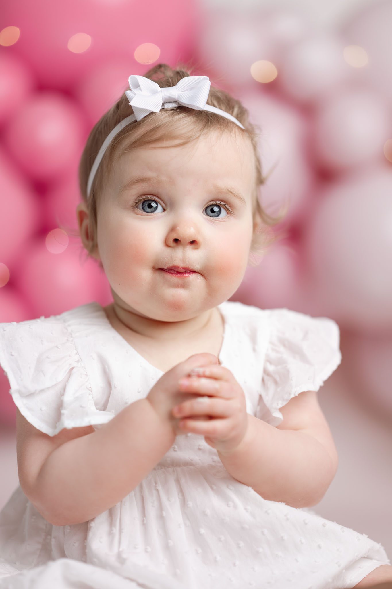 One twin girl covered in frosting happily eating a custom cake from V's Sweet Treats during her 1st birthday session.