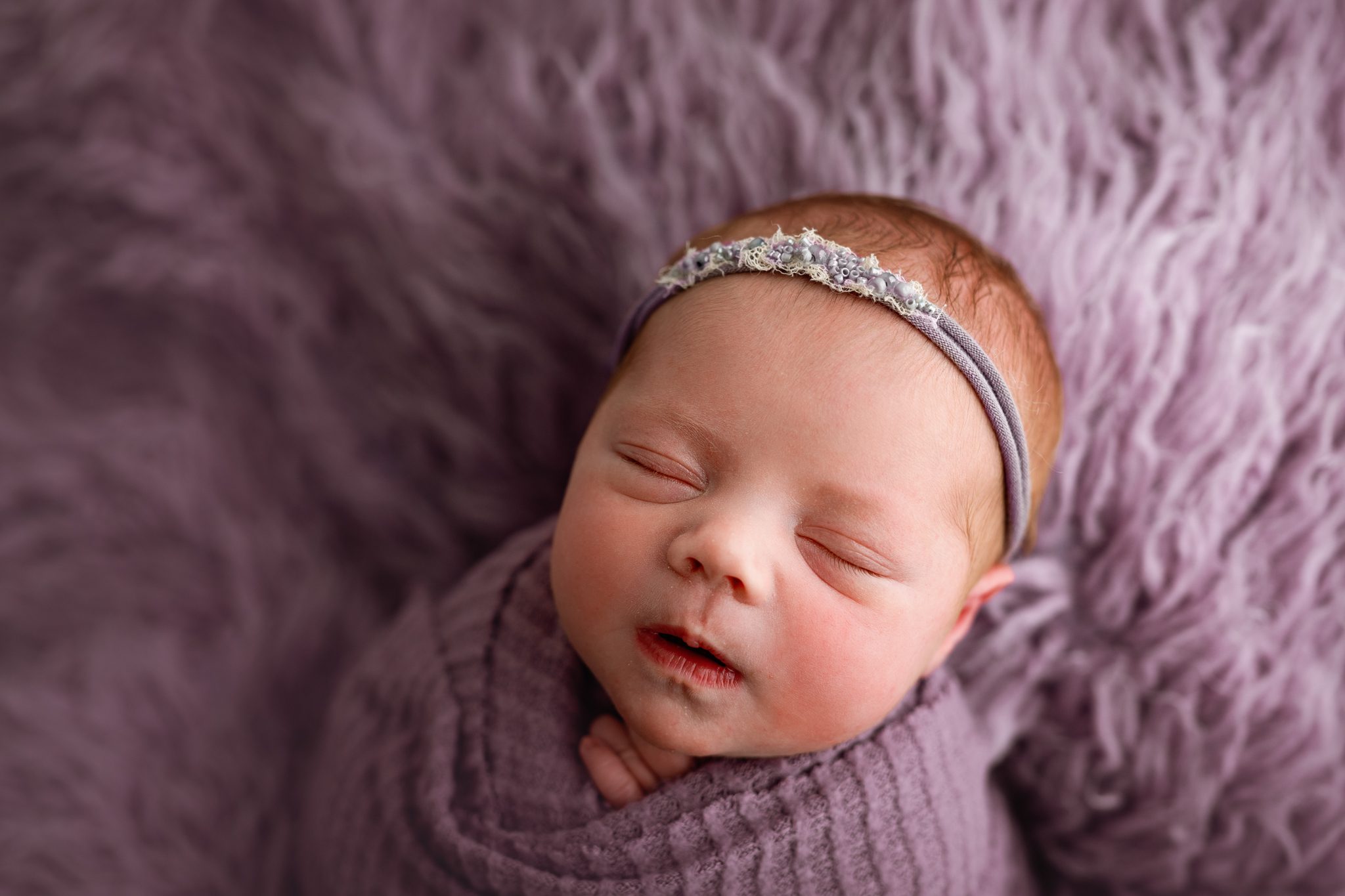 A sweet newborn redhead baby girl sleeping during a customizable newborn photoshoot in Scotch Plains.