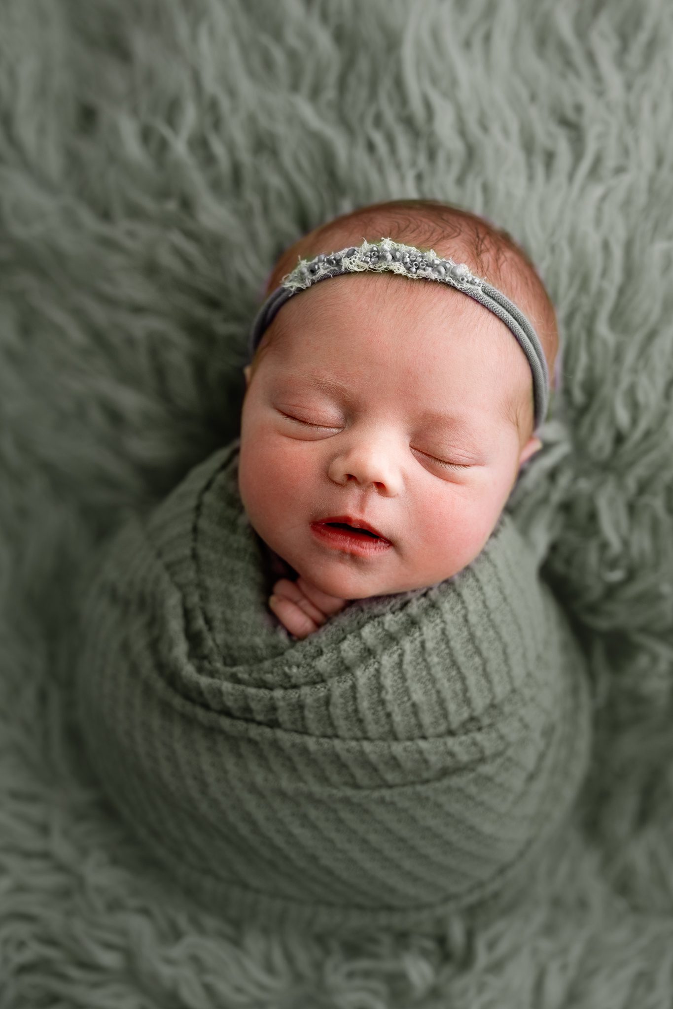 A sweet newborn redhead baby girl sleeping during a customizable newborn photoshoot in Scotch Plains.