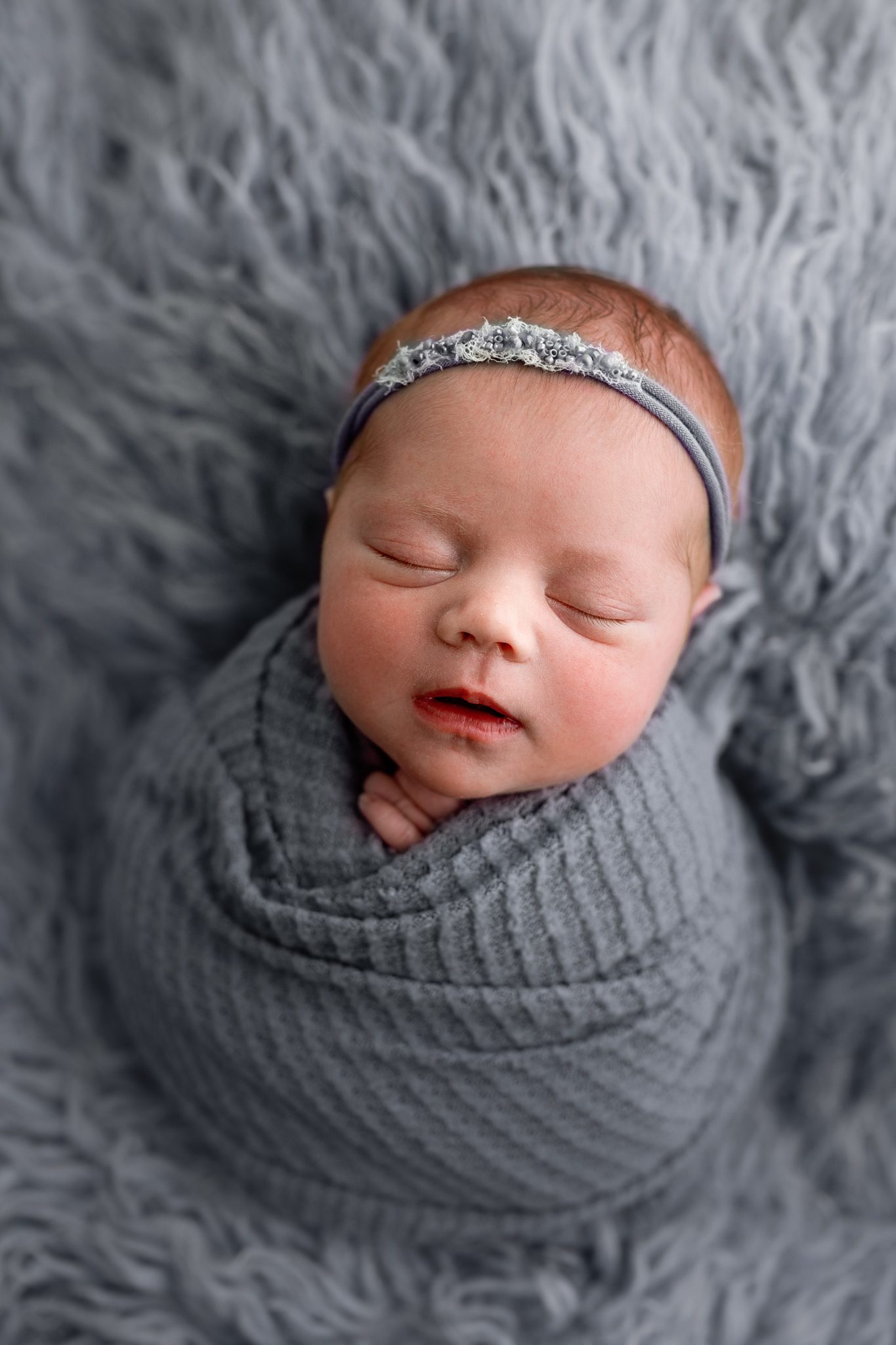 A sweet newborn redhead baby girl sleeping during a customizable newborn photoshoot in Scotch Plains.
