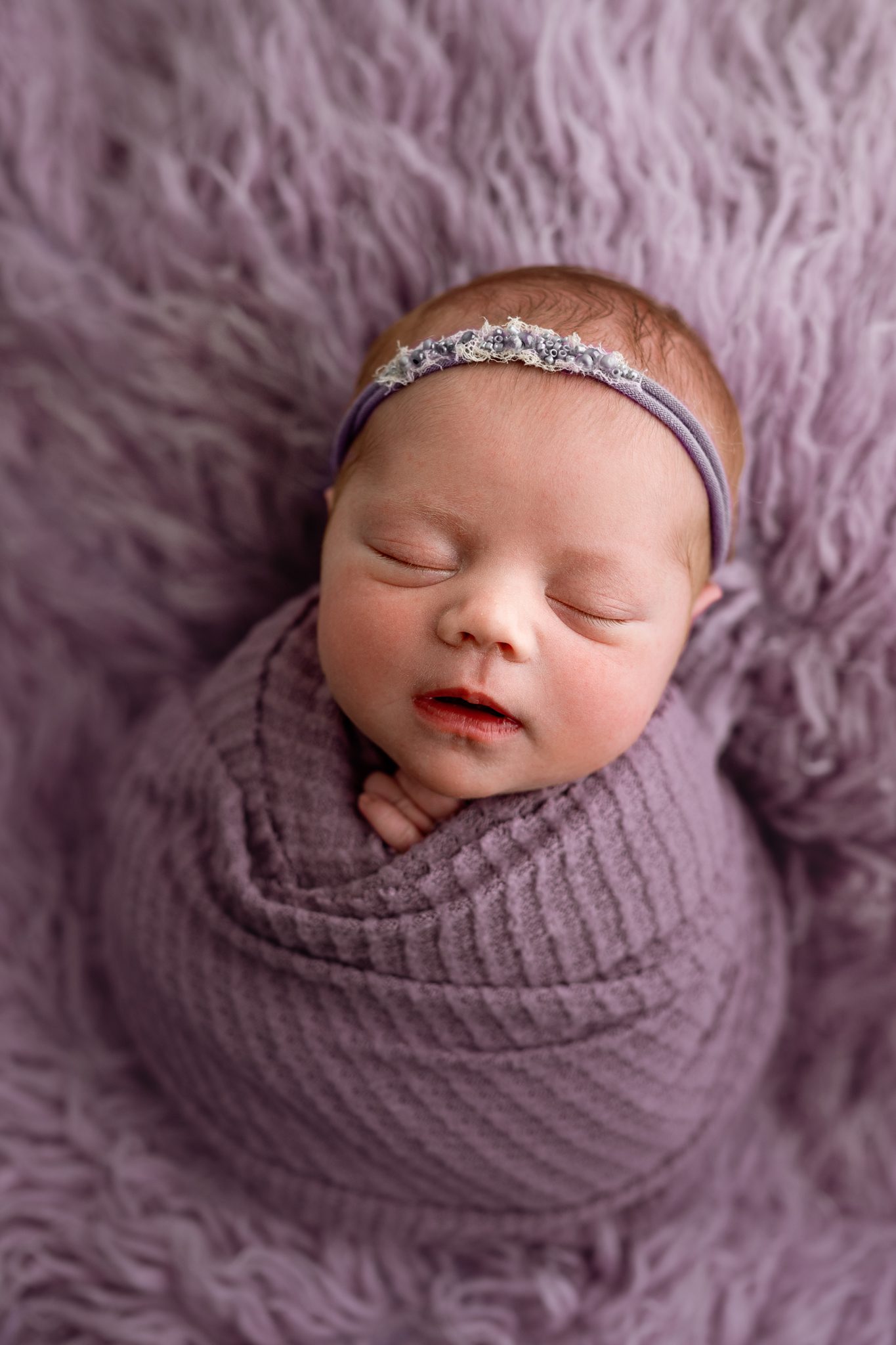 A sweet newborn redhead baby girl sleeping during a customizable newborn photoshoot in Scotch Plains.